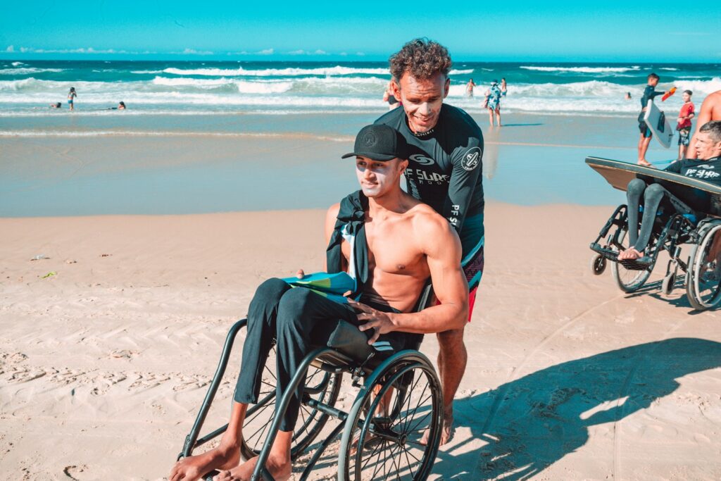 man in black shorts sitting on black wheelchair on beach during daytime